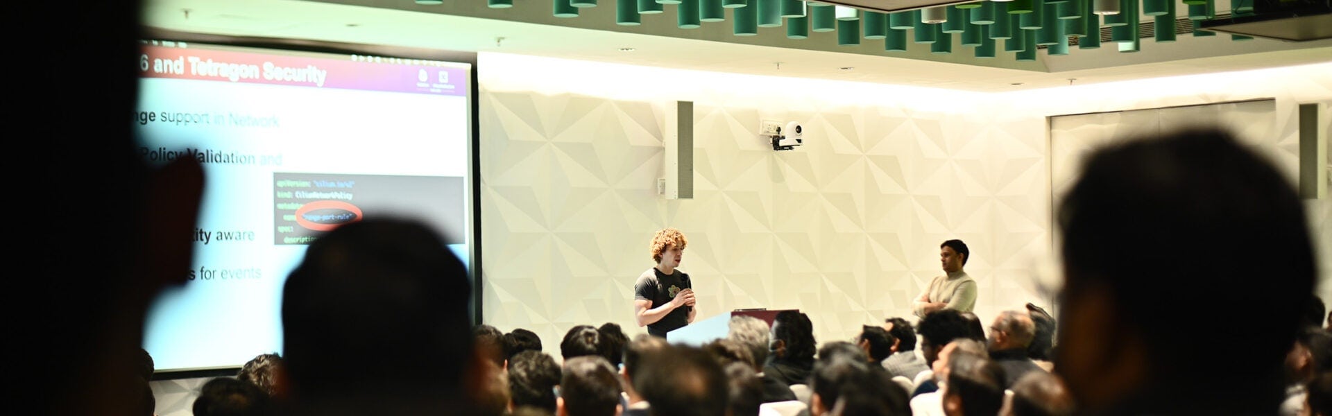A speaker stands at the front of a crowded room.