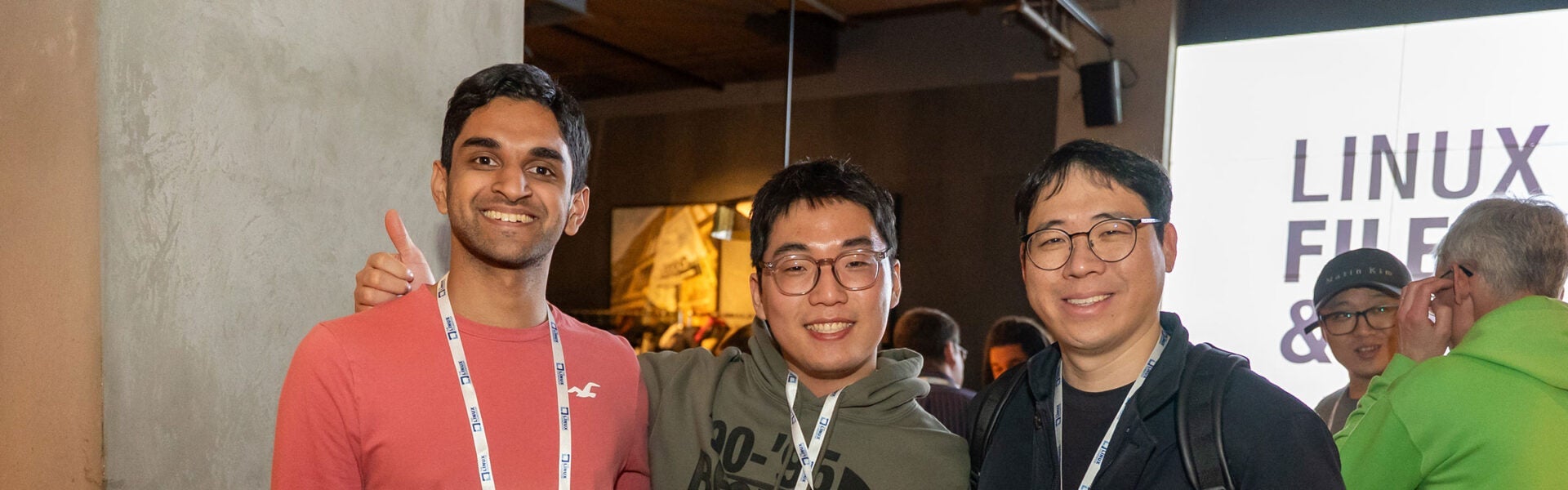 Three attendees smiling for a photo with one giving a thumbs up.