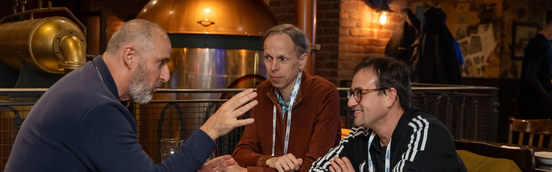 Three event attendees seated at a table engrossed in conversation.