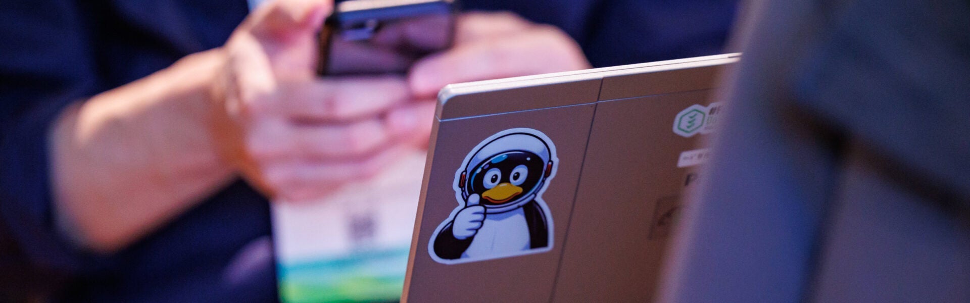 Stickers on a computer including tux in an astronaut helmet, giving a thumbs up.