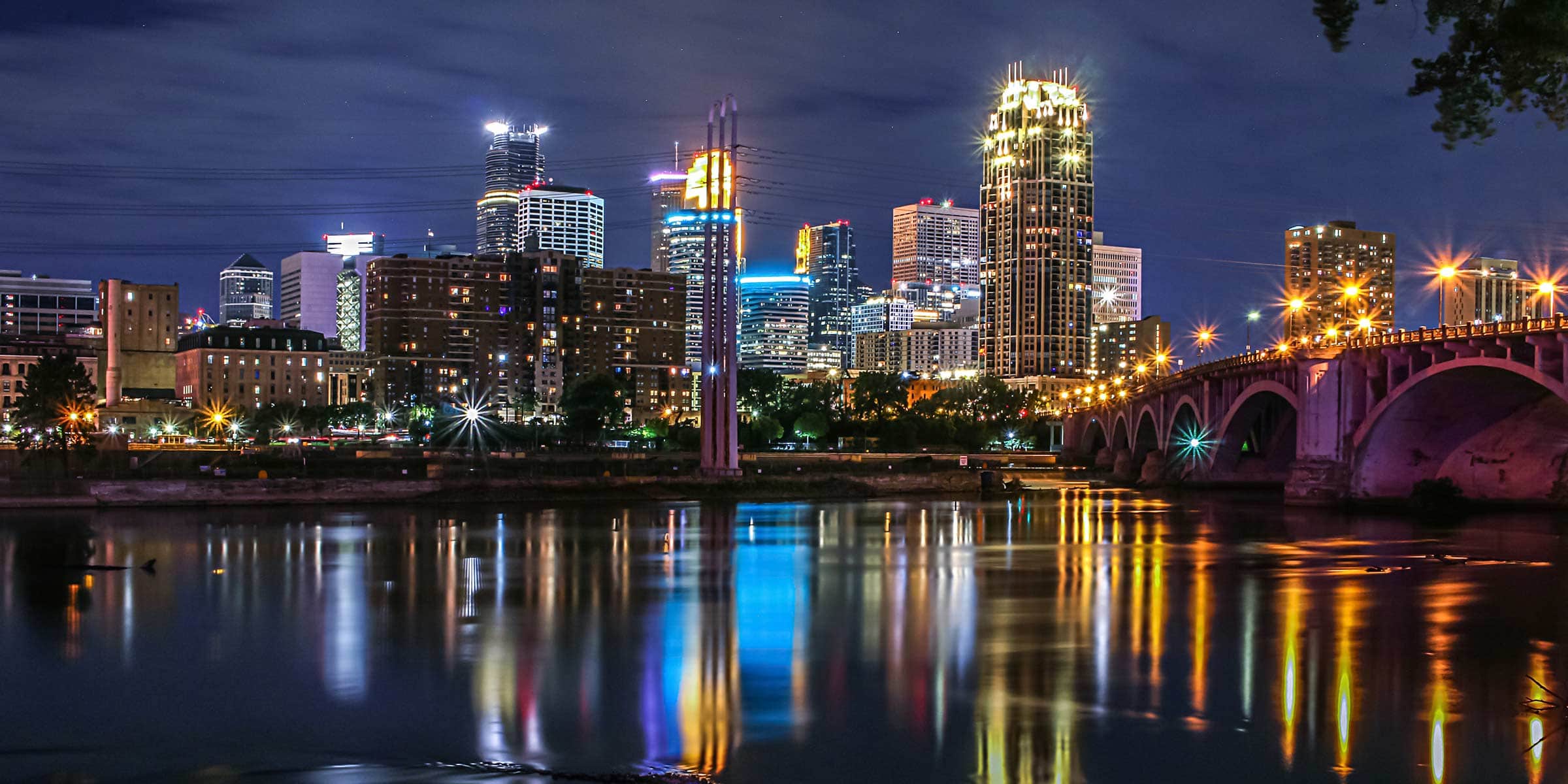 Minneapolis at night, with city lights reflecting on the Mississippi River.