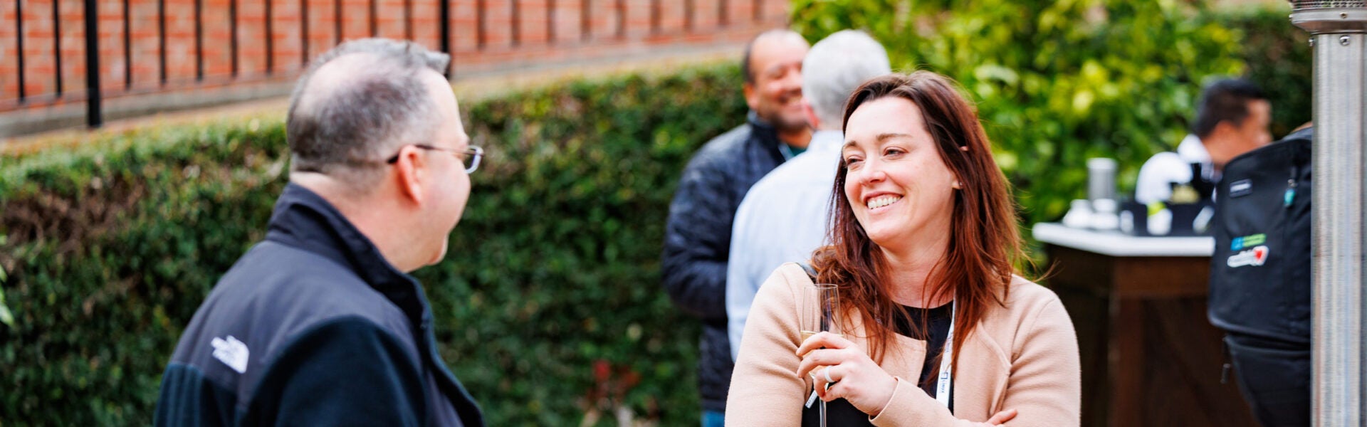 Two attendees standing outside, smiling and chatting with each other.