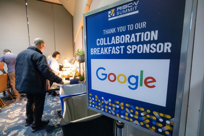 A sign that reads "Thank you to our collaboration breakfast sponsor Google" and a man serving himself food in the background.