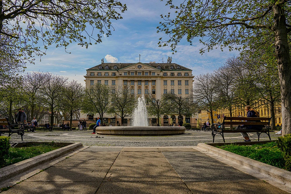 A walkway leading to a round fountain with the venue, Esplande Zagreb Hotel, in the background.