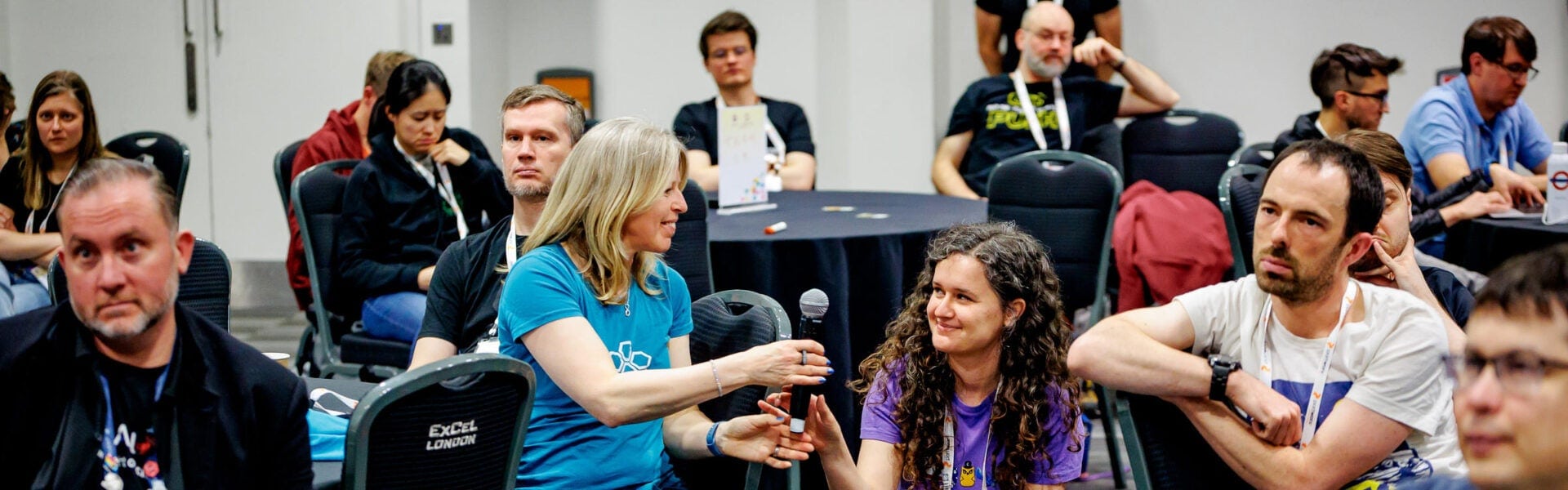 Attendees passing a microphone and appearing engaged in a discussion.