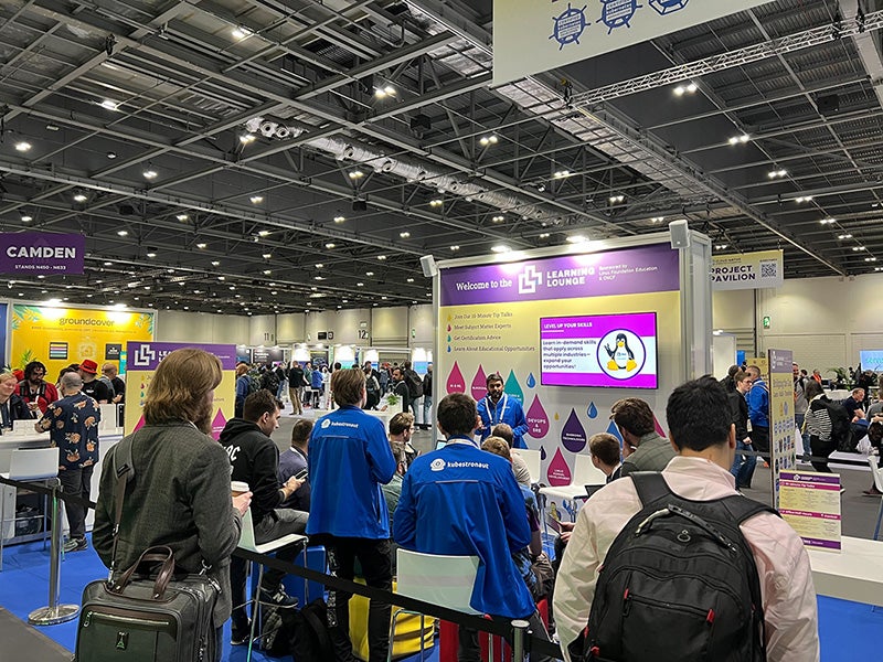 A large group of people facing a television listening to a speaker.