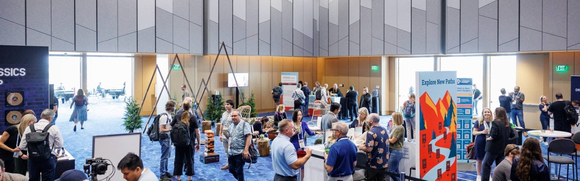 Attendees gather and network in an exhibit hall featuring sponsor booths, informational displays, and lounge areas during Open Source Summit.