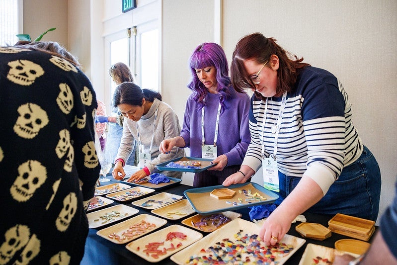 A group of attendees choosing items from trays on a table.