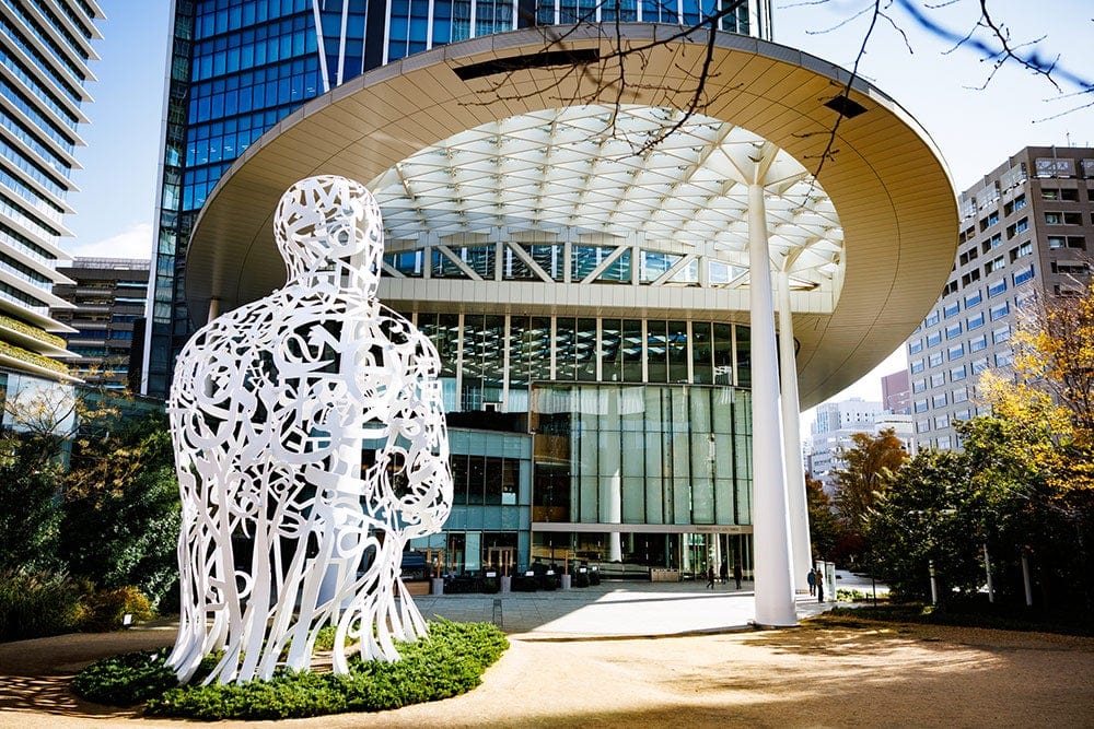 Large modern building at Toranomon Hills Forum with a white abstract sculpture in front.