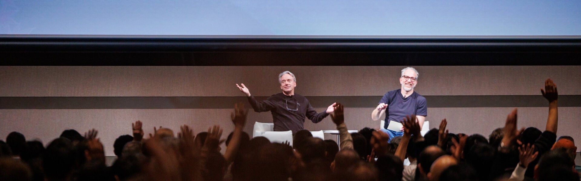 Two presenters on stage engaging with a cheering audience.