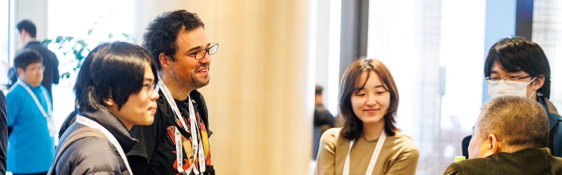 Attendees smiling and talking together in a conference hallway.