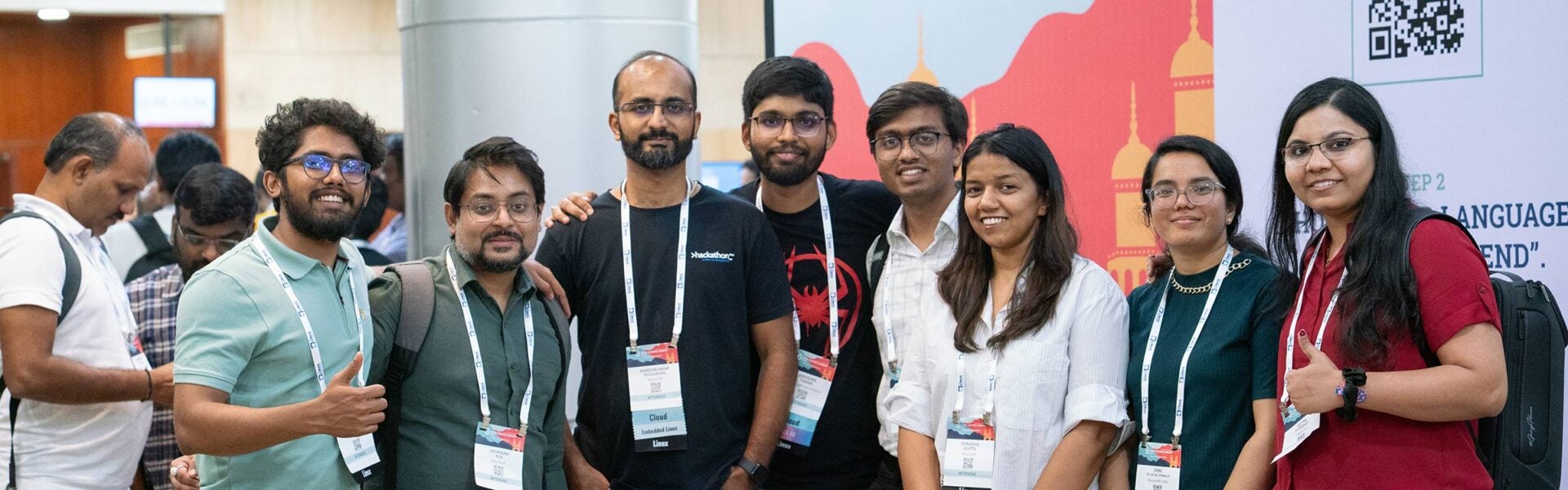 Group of conference attendees posing for a photo and giving thumbs up inside the event venue