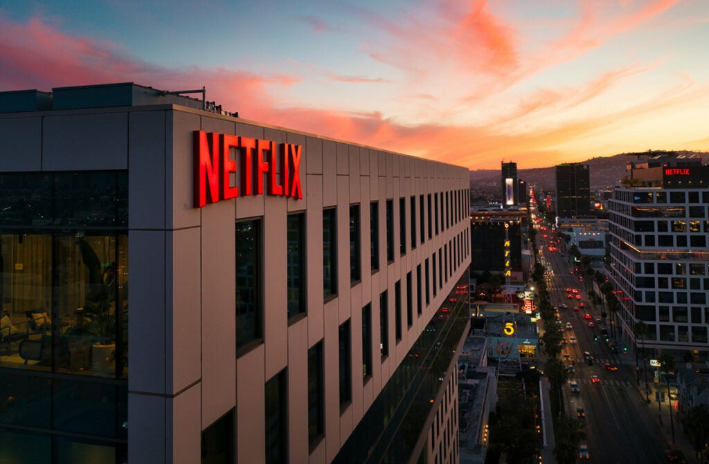 A white building with black windows and a Netflix sign at sunset.
