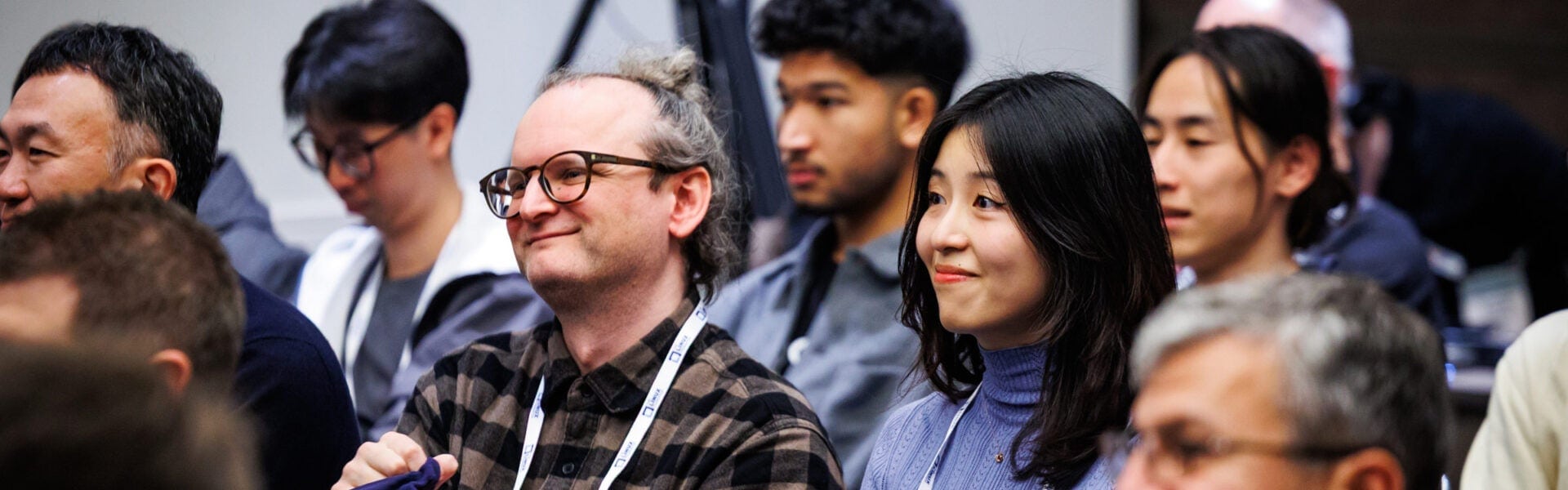 Audience members sitting and smiling while listening to a conference session.