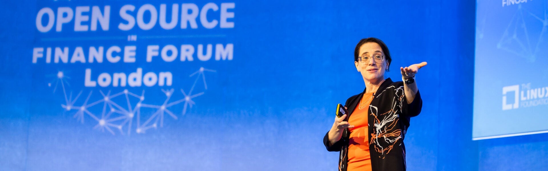 Speaker presenting on stage at an open source finance forum.