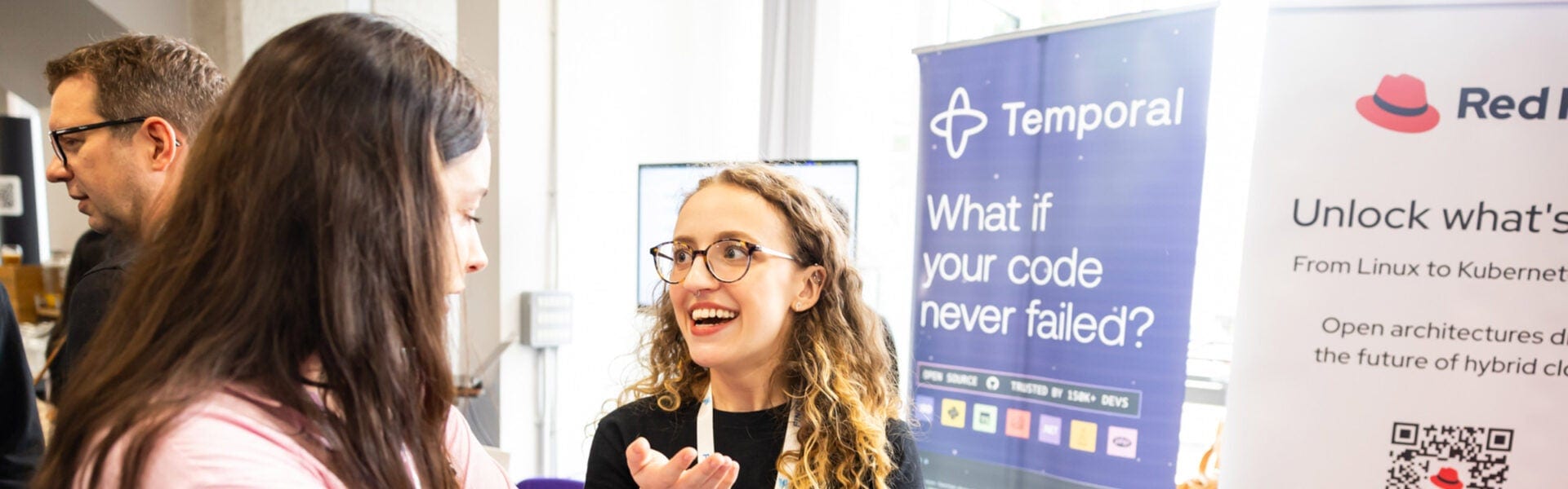 Exhibitors talking at a sponsor booth with banners displayed behind them.