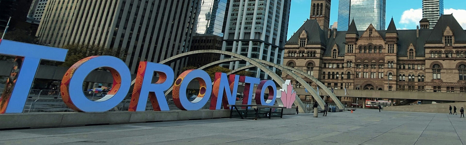 Large letters that spell "Toronto" in front of an old building.