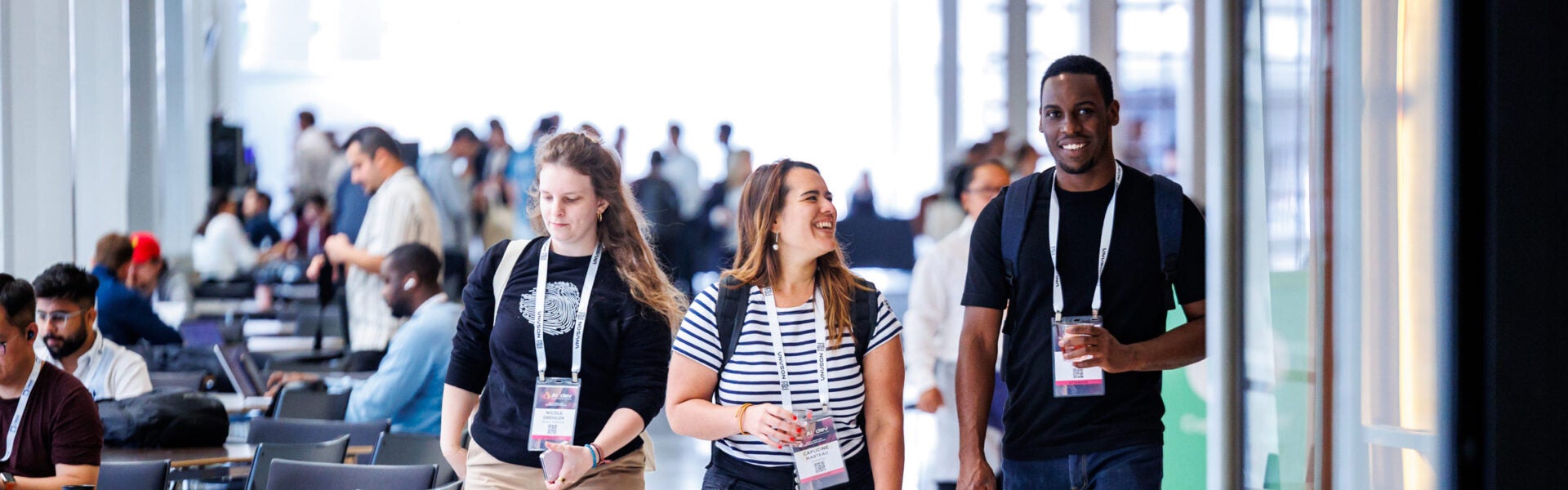 Conference attendees walking and chatting in a bright hallway