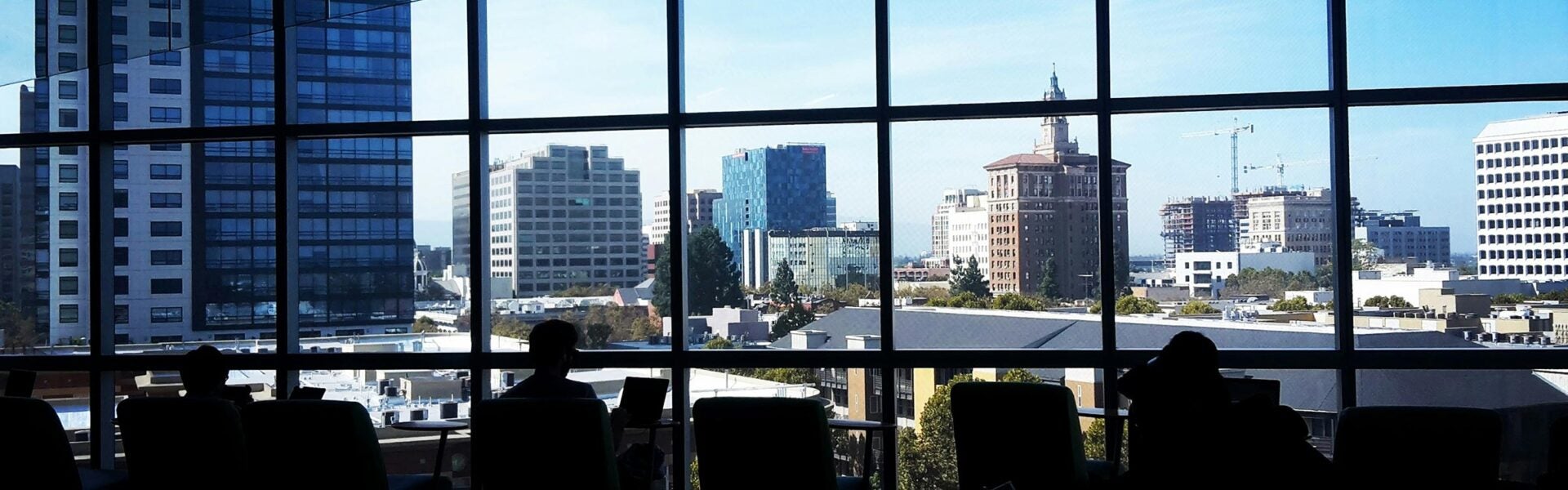 People seated by large windows overlooking a city skyline