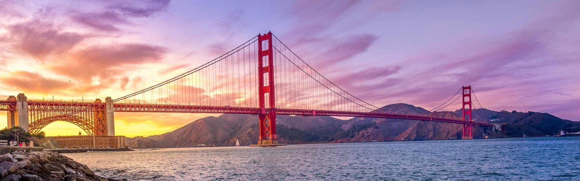 Golden Gate Bridge at sunset over the water.
