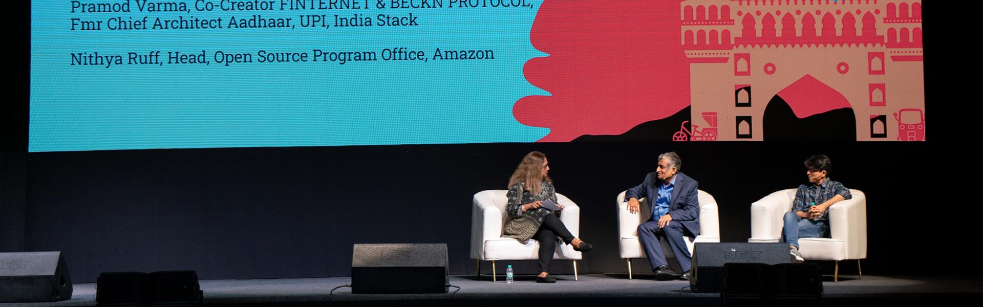 Three people sitting in chairs on a stage.