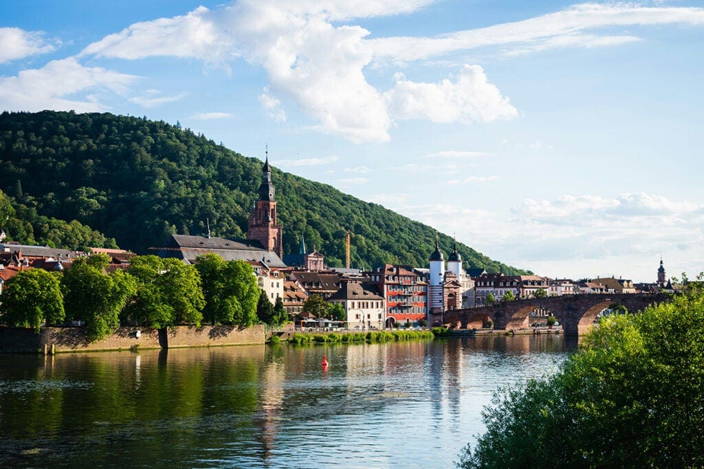 Stone buildings situated next to a river with a stone bridge crossing it.