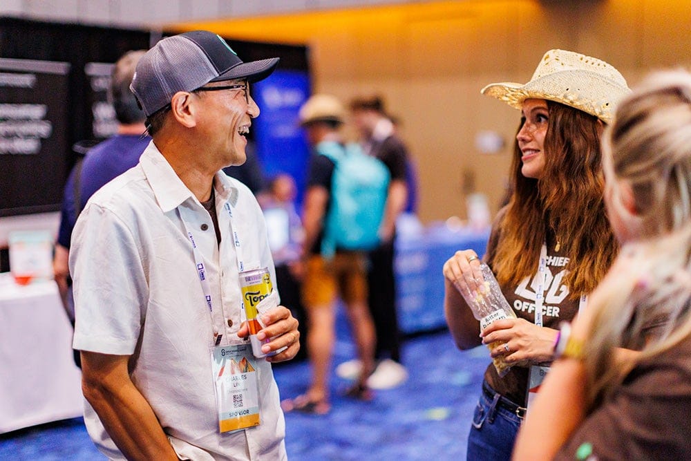 Attendees smiling and talking in a networking area.