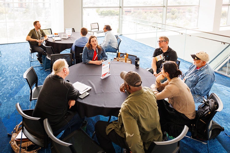 A group of attendees sitting at a round table having a discussion.