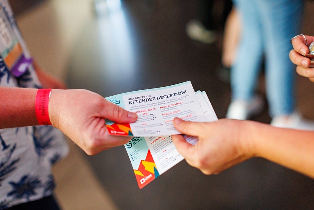 Staff member shares cards with reception details during a conference gathering.