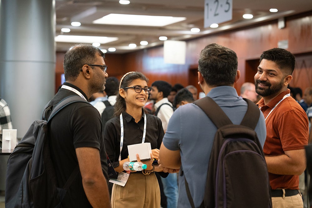 Conference attendees chat and smile while networking in a hallway.