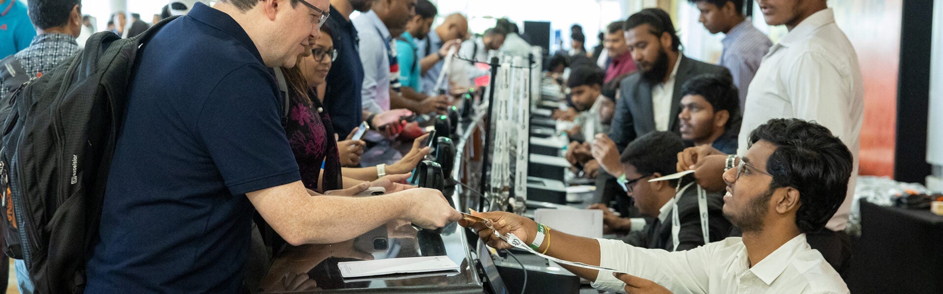 Attendees checking in at a registration desk, receiving badges and materials from event staff