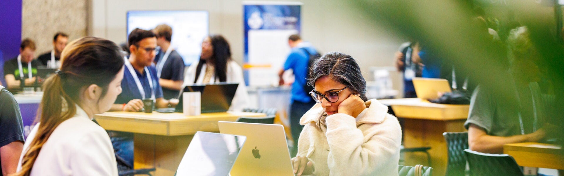 Attendees sitting at tables using their laptops.