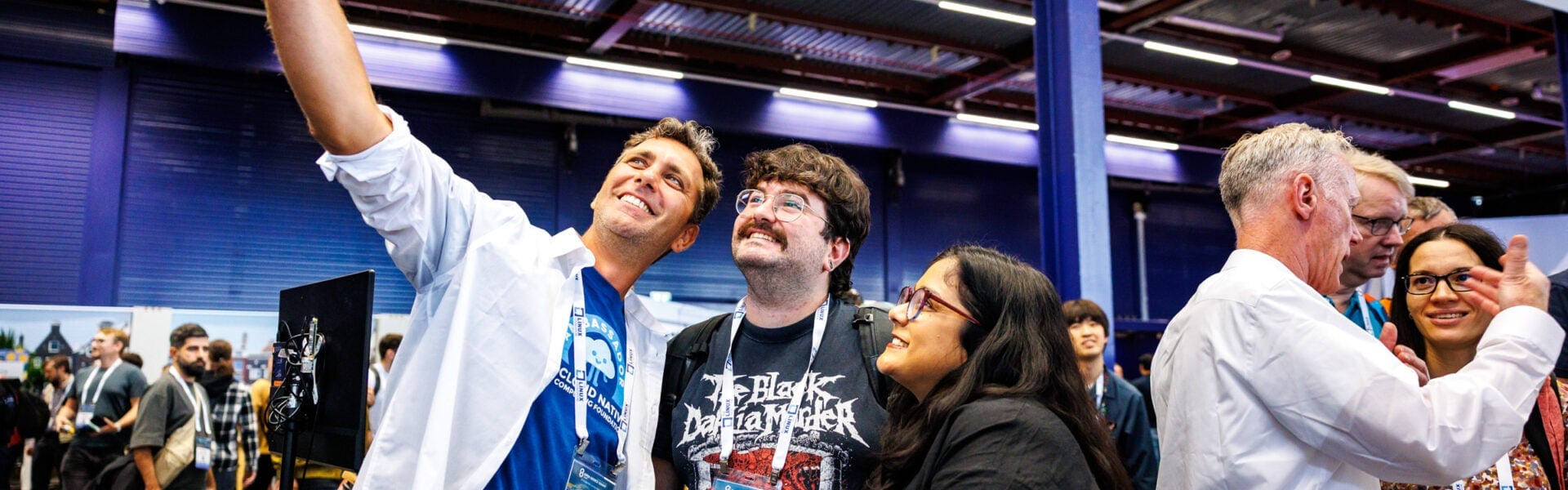 Attendees taking a group selfie in a crowded room.