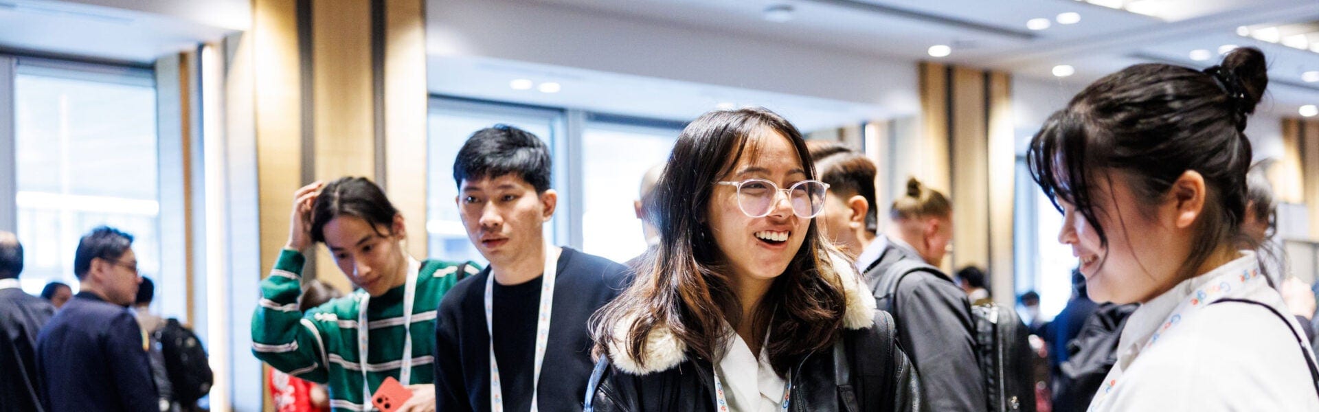 Attendees standing and chatting in a conference hallway, wearing badges and networking between sessions