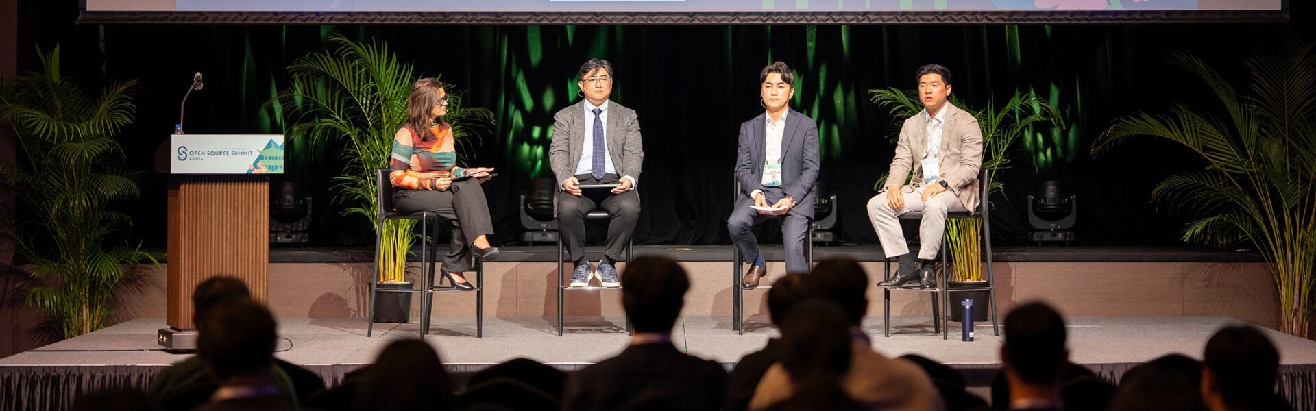 Panel discussion with four speakers on stage addressing the audience at Open Source Summit Korea.