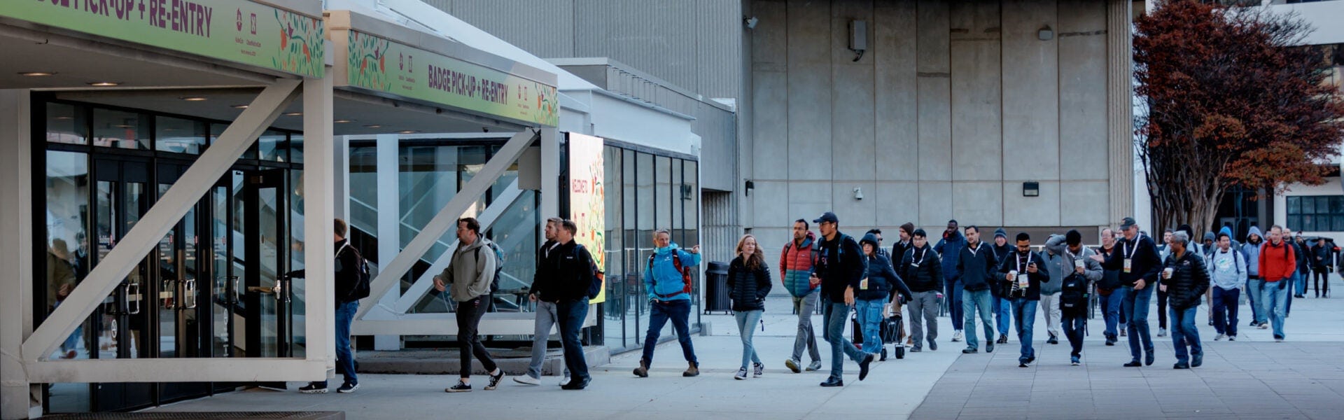 Attendees walk toward the convention center entrance for badge pickup and re-entry.