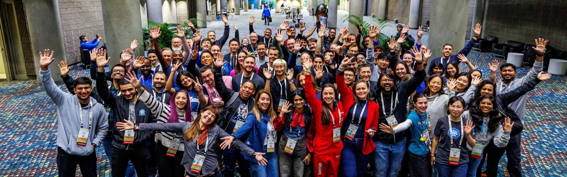 Large group of conference attendees gather and wave together for a group photo.