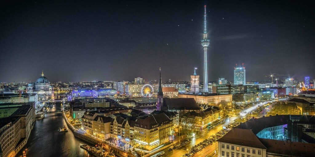 Nighttime cityscape of Berlin featuring the illuminated TV Tower and surrounding landmarks.