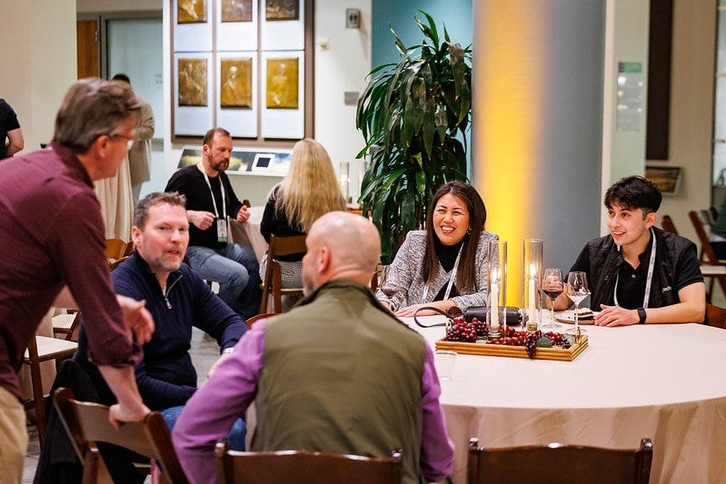 A group of attendees sitting at a round table having a lively discussion.