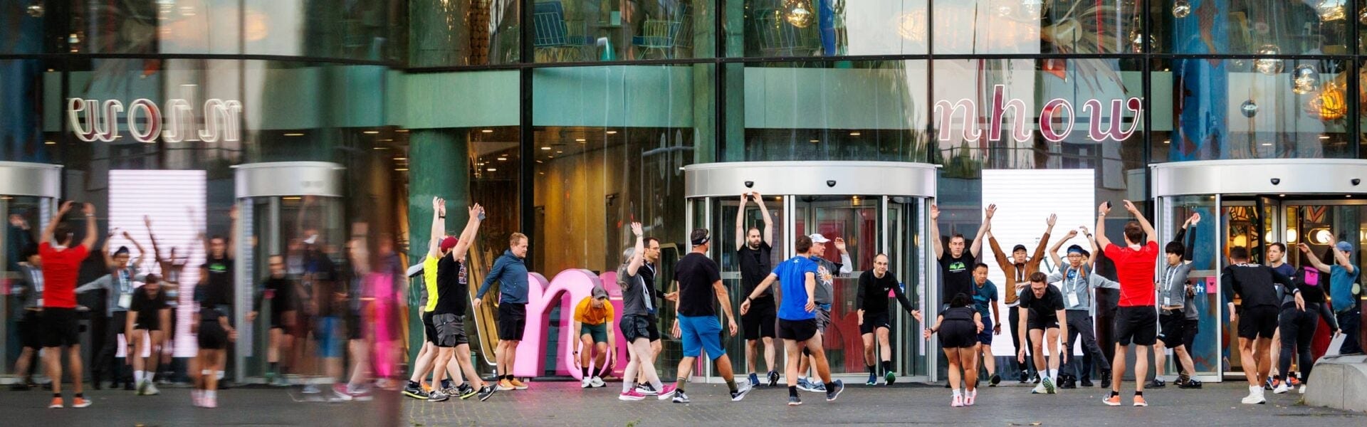 Group of conference attendees doing a warm-up outside a building entrance.