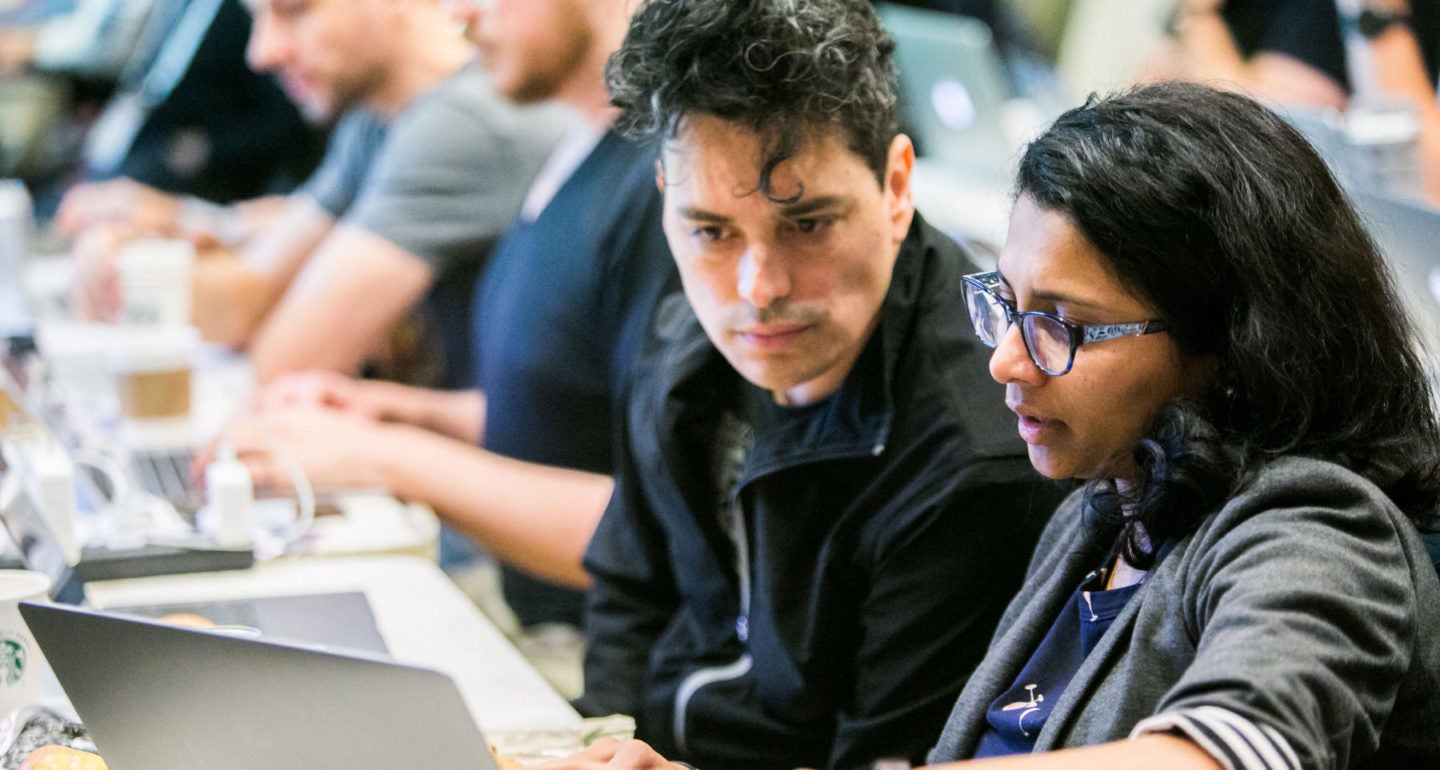 A man and woman discussing while looking at the laptop