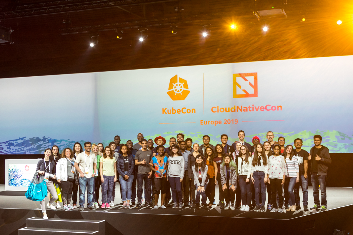 Large number of event attendees and speakers stand together on stage for a group photo